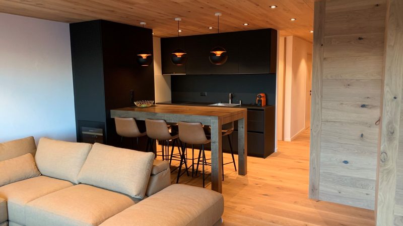 Un salon avec un canapé et une cuisine en arrière-plan