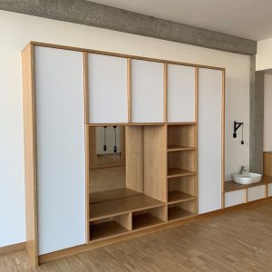 Une grande armoire en bois avec des portes blanches et des étagères dans une pièce.